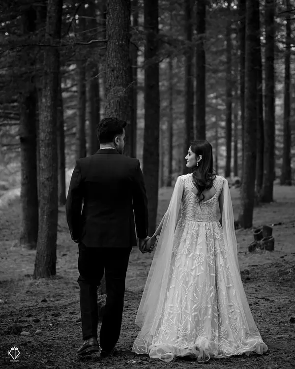 A timeless black and white shot of the couple walking hand-in-hand away into the dense forest, symbolizing the start of their journey together.