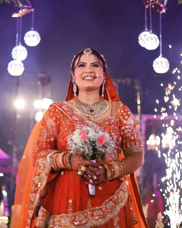 A bride's entry is a showstopper. Here, she walks in with a beautiful bouquet, her path lit by sparklers, creating a truly cinematic and unforgettable moment.