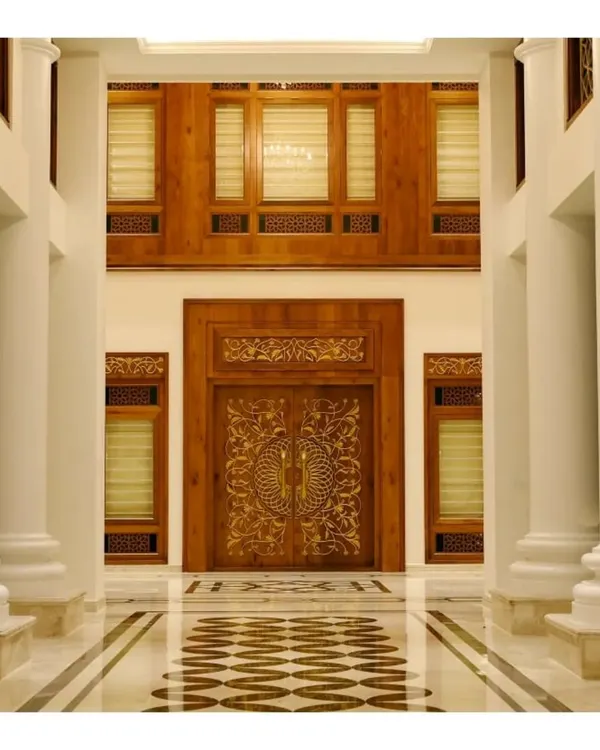 The main entrance of a Kerala-style luxury home, featuring a meticulously hand-carved wooden door set within a larger wooden frame. This design highlights our expertise in traditional woodworking and creating grand entryways.