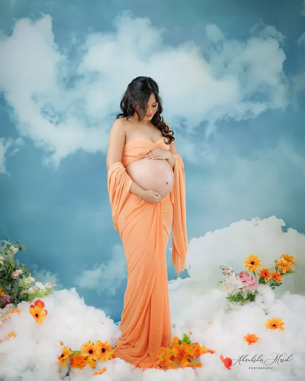 A goddess in the clouds. This dreamy setup, with a peachy fabric drape against a sky backdrop, creates an ethereal and heavenly portrait for the mother-to-be.