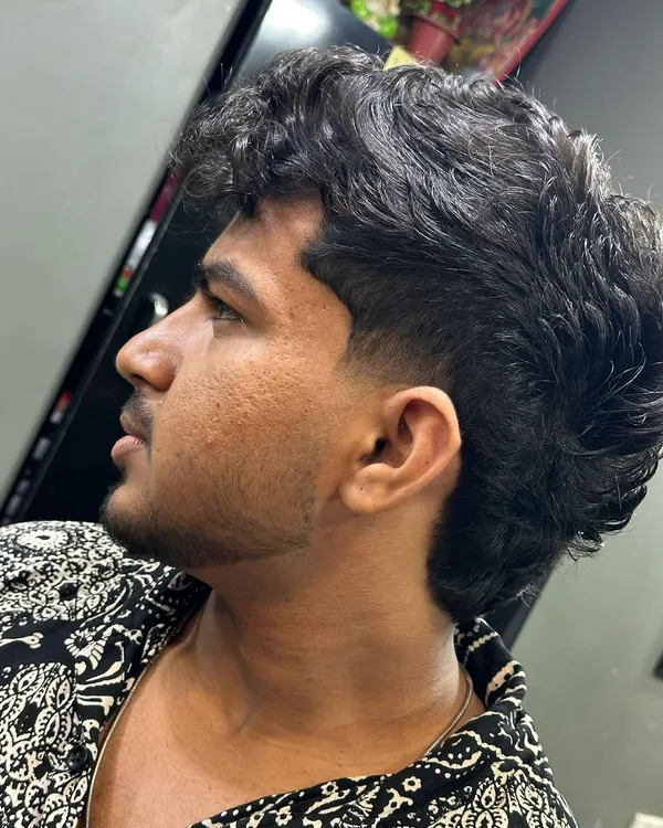 A modern mullet for curly hair. I kept the curls on top and in the back while giving the sides a sharp taper for a stylish contrast.