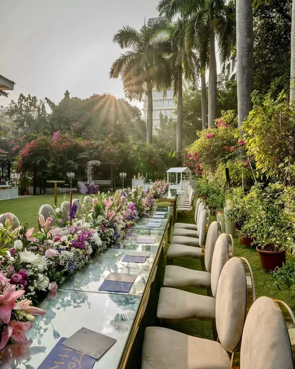 I designed this elegant outdoor setting for a corporate luncheon. The long, mirror-top table reflects the sky and lush surroundings, while the extensive floral runner in shades of purple and white creates a luxurious and inviting atmosphere for guests.