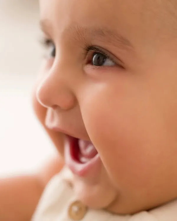 The purest giggle. This tight close-up captures the absolute joy of a baby's laugh, a perfect memory from a 6-month milestone session.