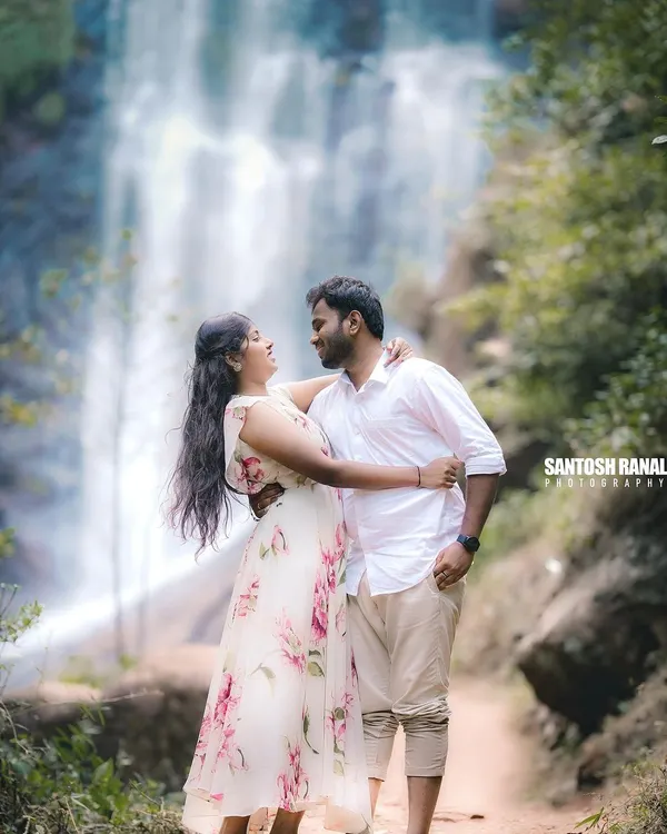 A romantic couple's portrait set against a stunning waterfall backdrop. This kind of epic, natural scenery is perfect for creating memorable pre-wedding or engagement photos.