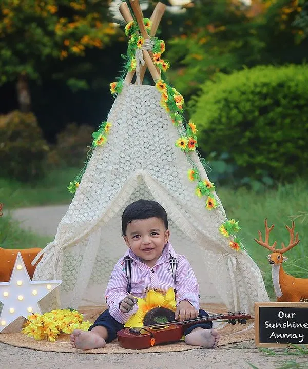Our little musician in his outdoor boho camp! This sitter session in the park features a teepee, woodland creatures, and a tiny guitar for a truly adorable photo.