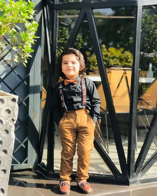 A young model looking sharp in an outfit I styled for a magazine shoot. This smart-casual look includes a black shirt, tan trousers, and fun Mickey Mouse suspenders.