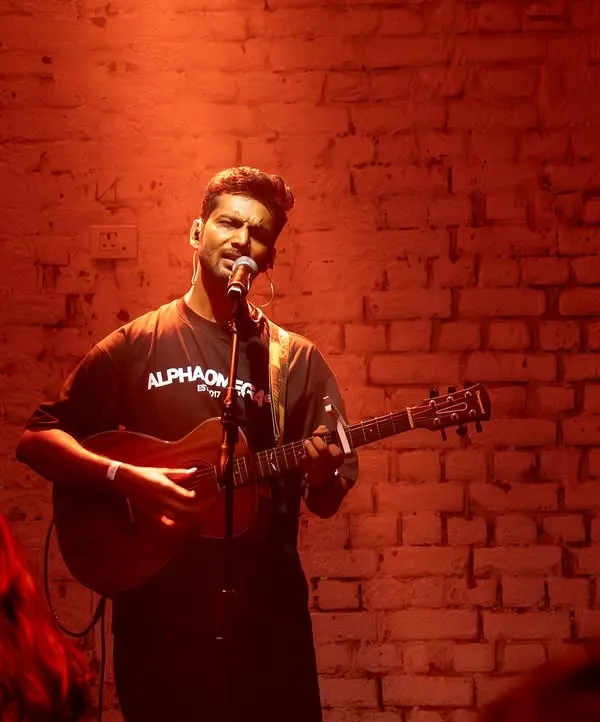 Performing a solo acoustic set at AntiSocial. The raw, intimate setting with the brick wall and red lighting created a powerful mood for an evening of indie music.