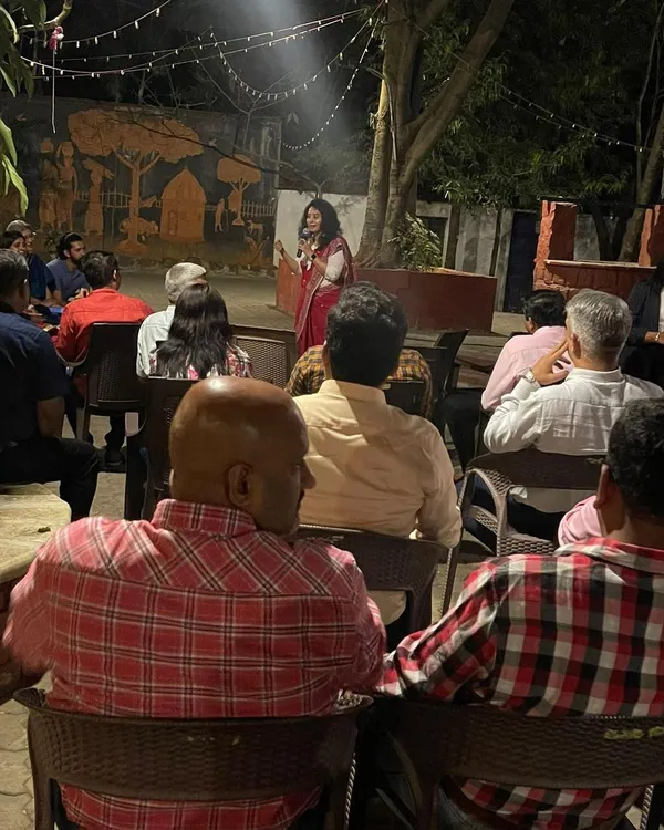 Hosting an evening event requires a different kind of energy. Here I am addressing an audience in a more informal, outdoor setting, creating a warm and engaging atmosphere.