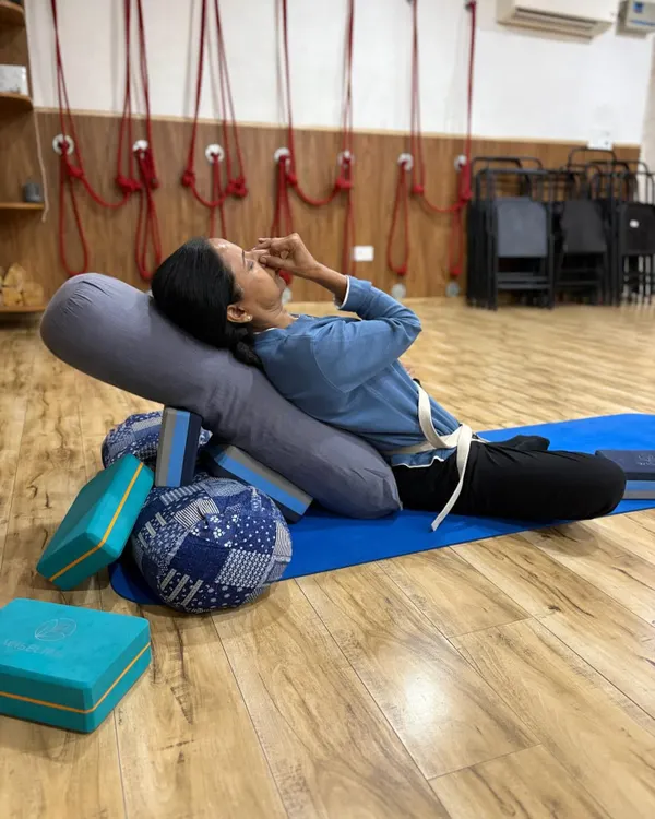 Here, a student practices Nadi Shodhana (alternate nostril breathing) while in a supported reclining pose. This combination of pranayama and restorative yoga is incredibly effective for calming the nervous system and reducing anxiety.