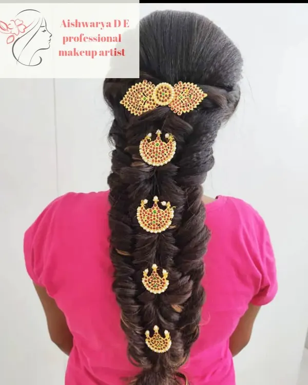 A classic South Indian bridal hairstyle featuring a thick fishtail braid. The braid is adorned with traditional temple-style hair jewels, which is a popular choice for muhurtham ceremonies.