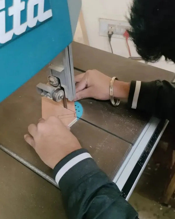 A student using the bandsaw to make a precise curved cut. This is part of a workshop where interior design students learn to use tools to build their own designs.