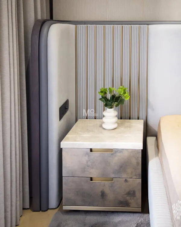 A detail of the Monarch Bed from a Suncity residence project. This shot shows the integrated bedside table with a marble top, set against the sculptural, upholstered panels of the extended headboard.