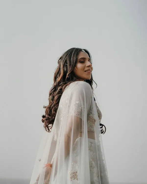 A beautiful solo portrait of the bride-to-be during her pre-wedding shoot. Her elegant white lehenga with a cape flows in the breeze, creating a dreamy and ethereal look.