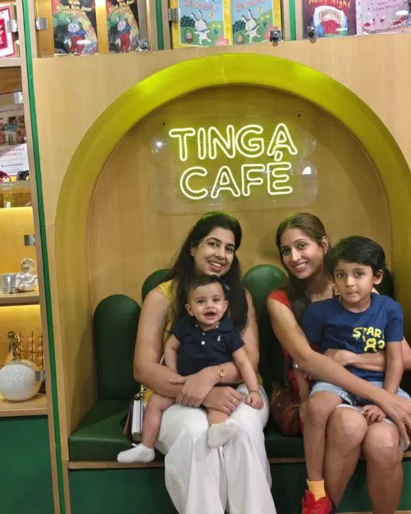 Two mothers relax at the Tinga Cafe with their young children, showing it's a comfortable space for the whole family.
