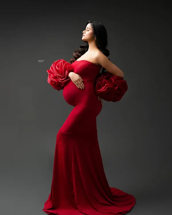 A portrait that is all about drama and elegance. This mamma looks absolutely stunning in our red Rosa gown, with its signature ruffled sleeves, against a classic dark studio backdrop.