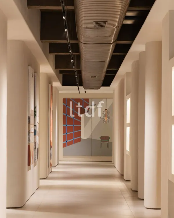 This corridor is designed to be more than a passageway; it's a spatial narrative in motion. The disciplined rhythm of the columns and the contrast between raw industrial ceiling elements and curated art invites both reflection and interaction.