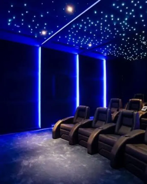 We bring the cosmos into your home with custom fiber optic starry night ceilings. This setup, combined with deep blue ambient lighting and premium leather recliners, creates an unparalleled, dream-like movie-watching environment.