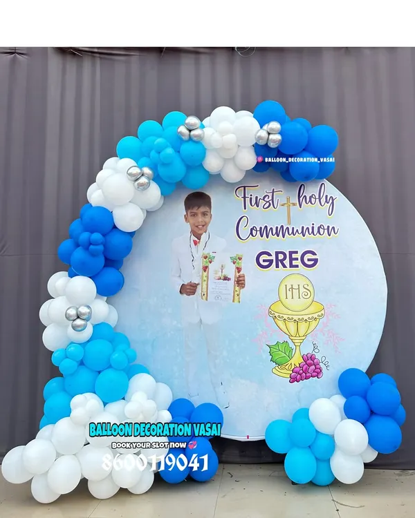 A beautiful decoration for a First Holy Communion. The round backdrop features a custom design and is framed by a blue and white balloon arch.