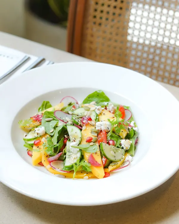Our seasonal baby spinach and Alphonso mango salad. This refreshing dish combines sweet mango, crisp cucumber, and creamy feta, capturing the taste of summer in a bowl.