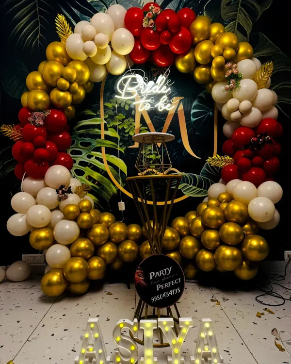 I designed this vibrant 'Bride to be' setup featuring a circular backdrop with a dense balloon garland in red, gold, and white. The bright 'Bride to be' neon sign and custom marquee letters for the name 'AISYA' create a personalized and photo-ready focal point for any bachelorette party.
