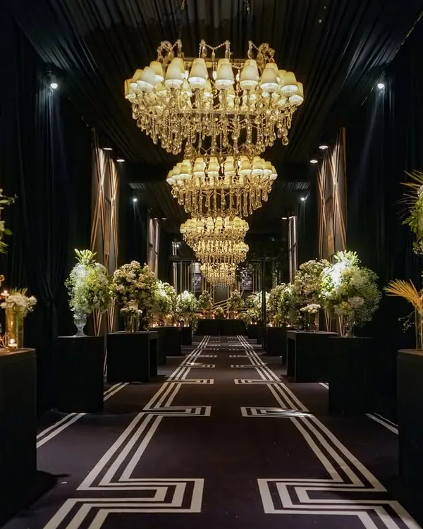 The entrance to this 25th-anniversary party was a grand hall of mirrors and memories. Massive chandeliers hung overhead as guests walked past a gallery of the couple's photos, creating a deeply personal and glamorous welcome.