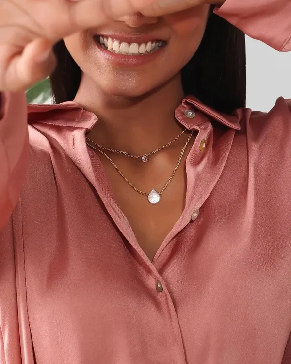 A close-up shot perfectly capturing the delicate details of a layered necklace. The focus is entirely on the product, showing its elegance and how it sits on the neckline.