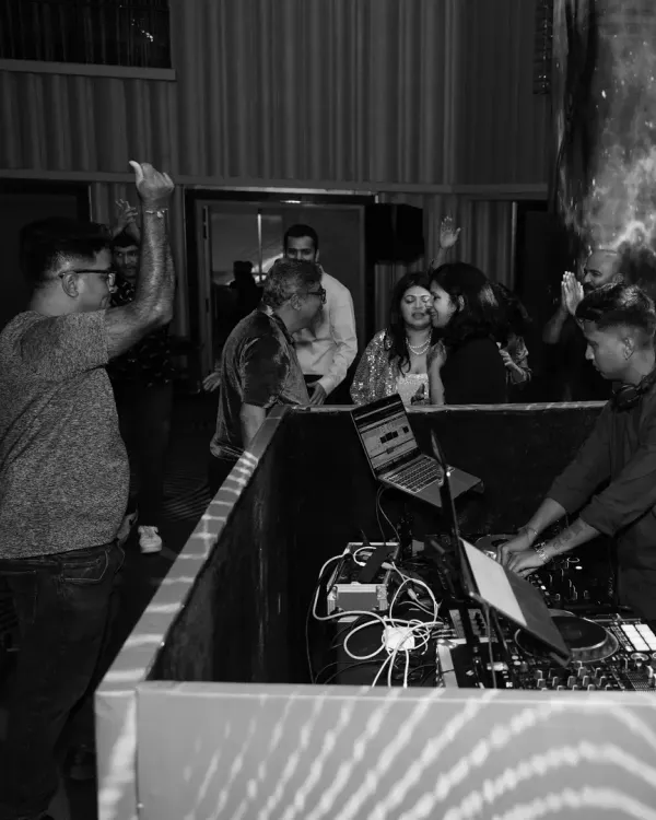 A black and white shot capturing the timeless energy of a retro night. You can see guests interacting with me at the DJ booth, fully immersed in the classic tunes.