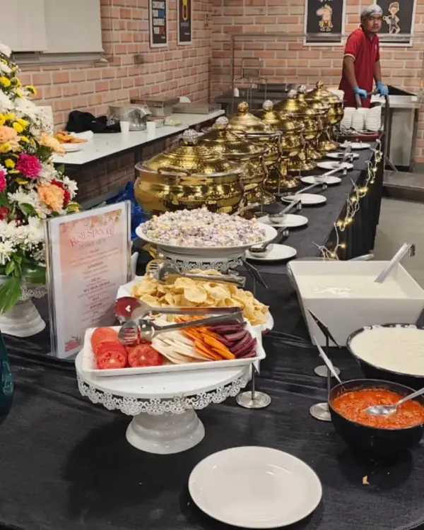 Our specialty is creating impressive buffet spreads that become the centerpiece of any event. This setup for a corporate gathering features a full multi-course menu, including fresh salads, main courses in our signature copper pots, and a variety of condiments, all beautifully presented with floral arrangements.