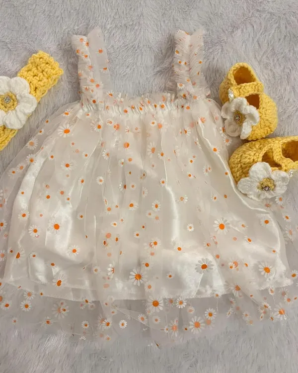 This daisy-themed set combines a delicate net frock with a soft satin lining for comfort. I've paired it with a handmade crochet headband and booties, both featuring a matching daisy flower.