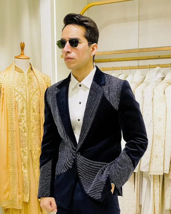 This is how you own the room at a reception. A custom-tailored navy velvet blazer featuring waves of shimmering beadwork on the lapels, shoulders, and cuffs for a truly standout look.