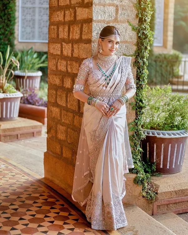 A full view of a breathtaking custom ensemble. We designed the 3D floral embroidered blouse, the intricately worked saree border, and the delicate sheer veil to create this cohesive and regal look for the bride.