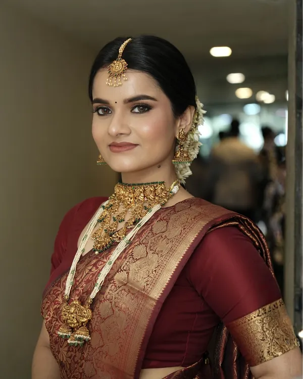 This is the epitome of South Indian bridal glam. I created a flawless matte base, defined the eyes with classic liner, and paired it with a rich lip color to complement the maroon silk saree and heavy temple jewelry.