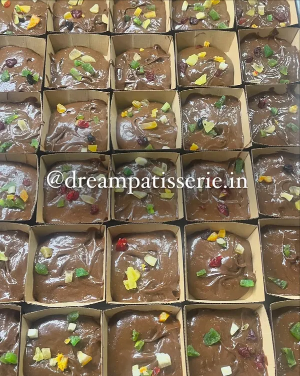 Preparing a large corporate order for Christmas. These are our rich plum cake batters topped with candied fruits before baking.