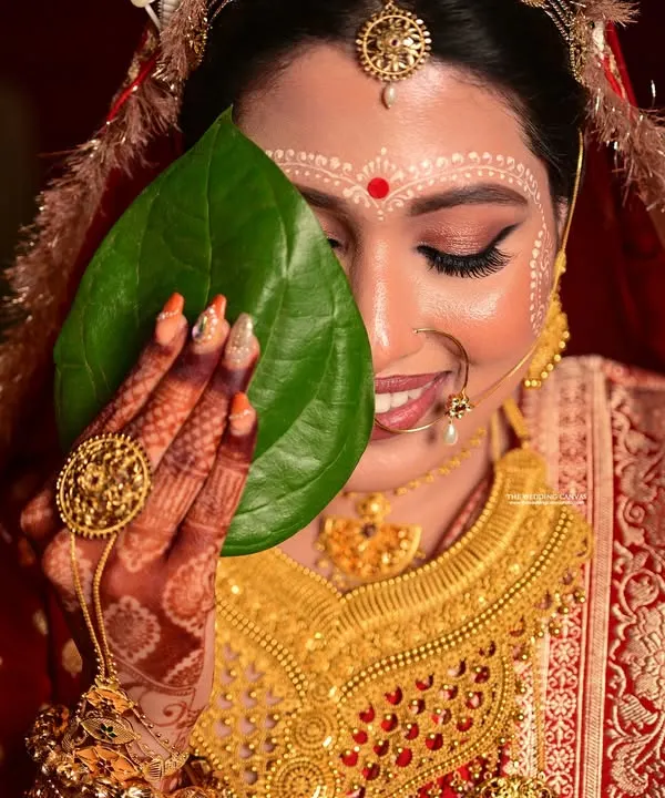A classic Shubho Drishti moment. The bride's shy smile behind the betel leaves is a cherished part of the Bengali wedding ceremony, and I aim to capture its innocence and beauty.