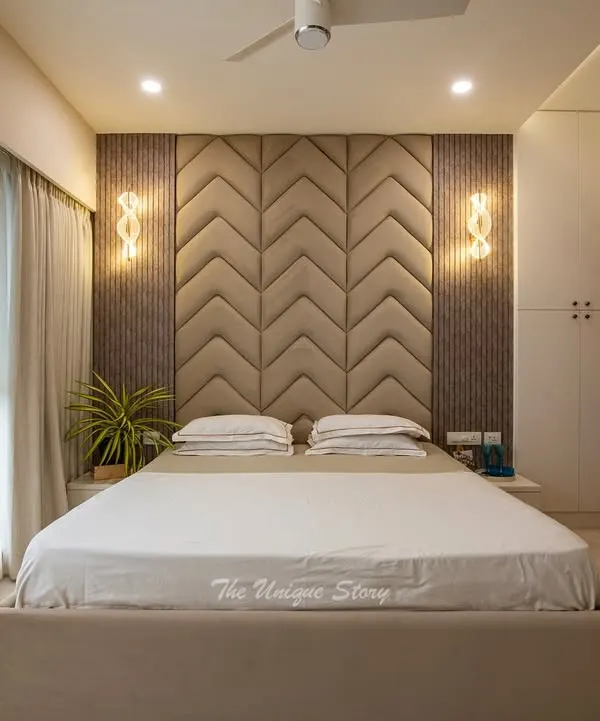 This modern master bedroom is a study in texture and tranquility. We designed a custom chevron-patterned upholstered headboard as the centerpiece, flanked by elegant wall sconces and fluted wall panels to create a sophisticated and restful retreat.
