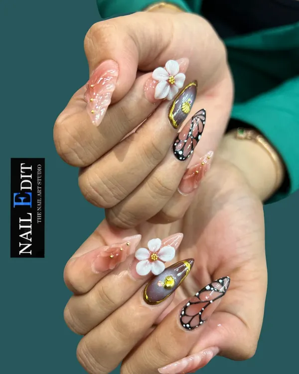 This set demonstrates our mastery of mixed-media nail art on long, stiletto extensions. We've combined delicate, hand-sculpted 3D white flowers, detailed butterfly wing art, and a rich chrome finish with gold accents for a truly statement-making look.