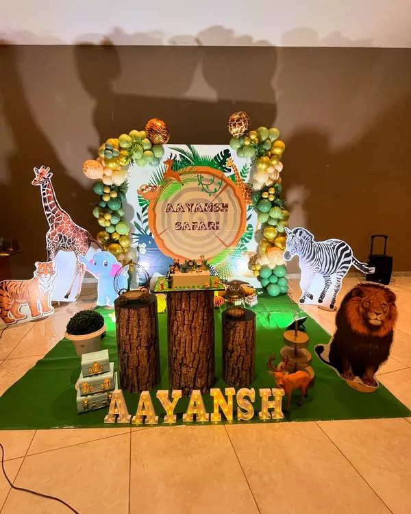 A fantastic jungle safari theme for Aayansh's birthday. The setup includes a giraffe, zebra, and lion, with a custom 'Aayansh Safari' backdrop and marquee letters.