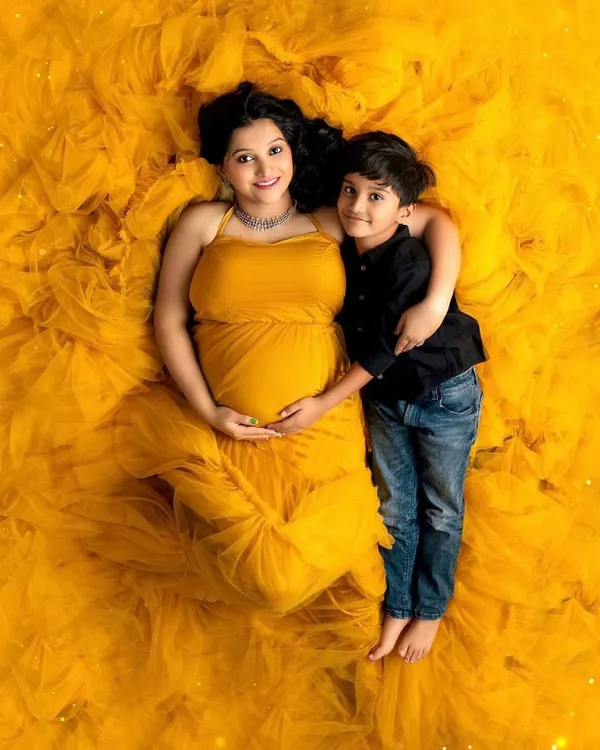 The journey to motherhood is a universe of its own. This stunning overhead shot celebrates the beauty and power of a mother-to-be, wrapped in a vibrant gown that's as full of life as she is.