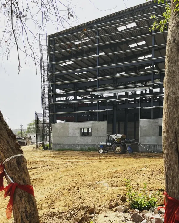 A factory building under construction, revealing its massive steel frame. We apply the same principles of structural clarity and functional design to our industrial projects as we do to our residences.