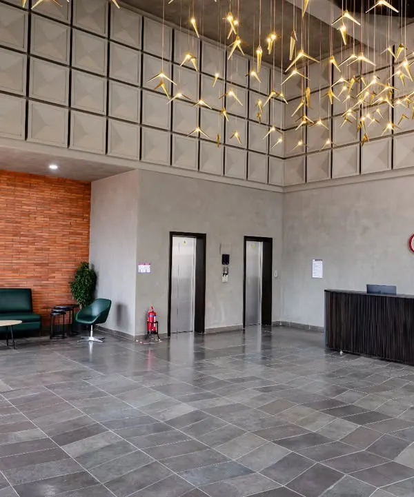 The main entrance lobby at Anthea Pharma, a 12,000 sq. ft. space combining industrial design with natural elements. The flooring is natural grey limestone, complemented by an exposed brick wall and microtopped cement finishes, creating a harmonious interplay of rugged textures.