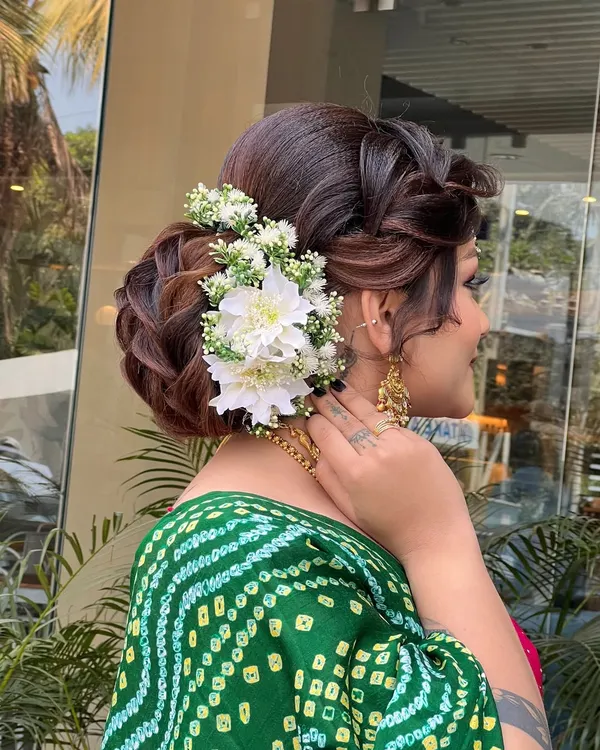 This is one of my favorite bridal updos, perfect for a wedding ceremony. I created this intricate braided bun and adorned it with fresh white flowers to match the bride's beautiful green bandhani saree.