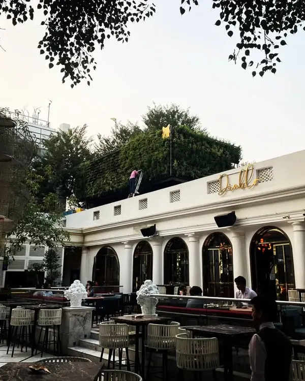 A wide view of the outdoor dining area at Diablo restaurant in Mehrauli. Our landscaping work, including the green walls and large trees, helps create a sophisticated, open-air ambiance.