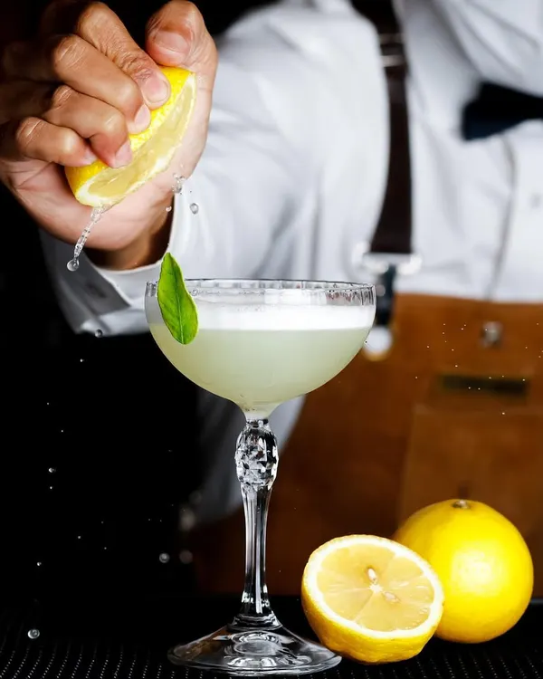 Capturing the action of a lemon being squeezed into a cocktail, this shot is all about freshness and craft.
