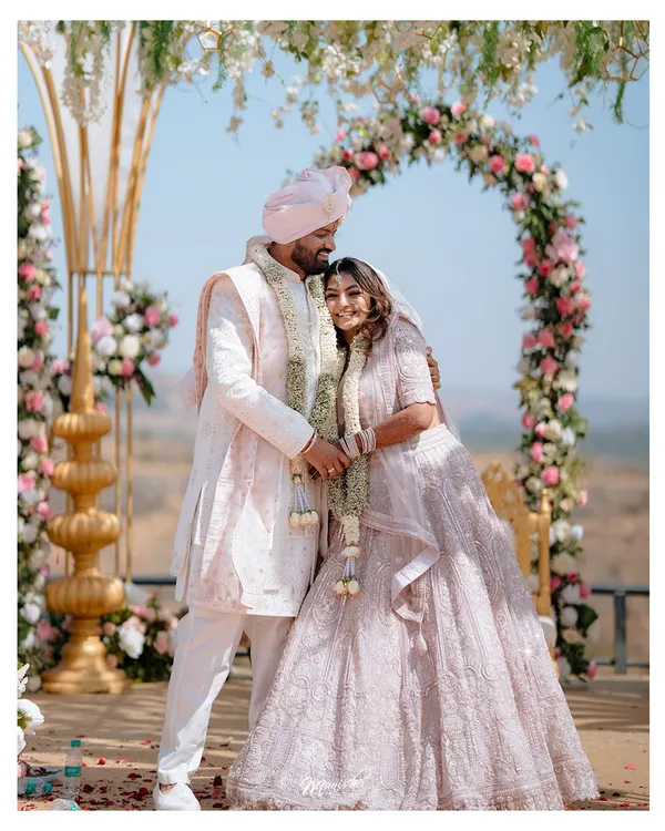 A moment of quiet connection amidst the grandeur of the wedding ceremony. The couple stands before a beautiful floral arch, ready to begin their new life together.