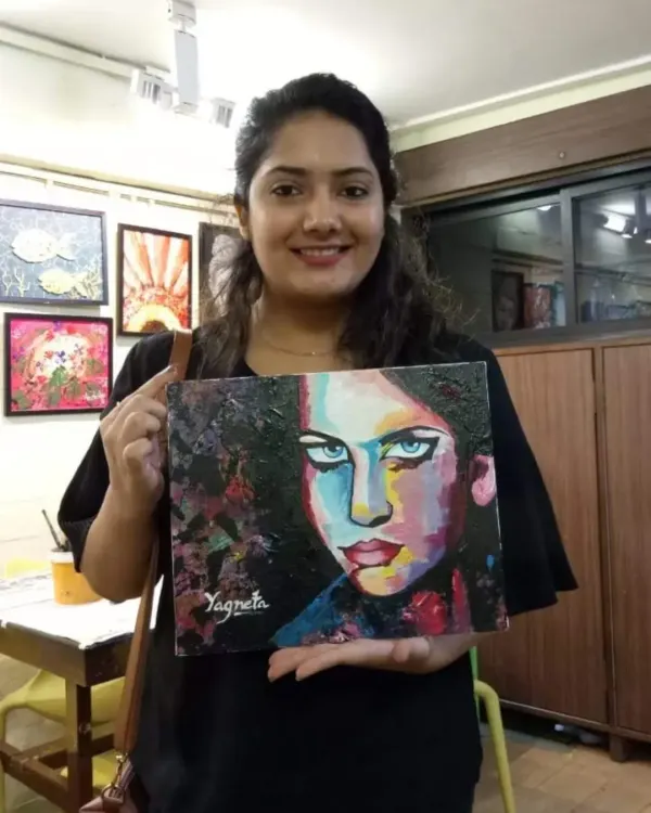 This student proudly displays her vibrant portrait, a result of exploring bold colors and knife painting techniques in our adult acrylics class.