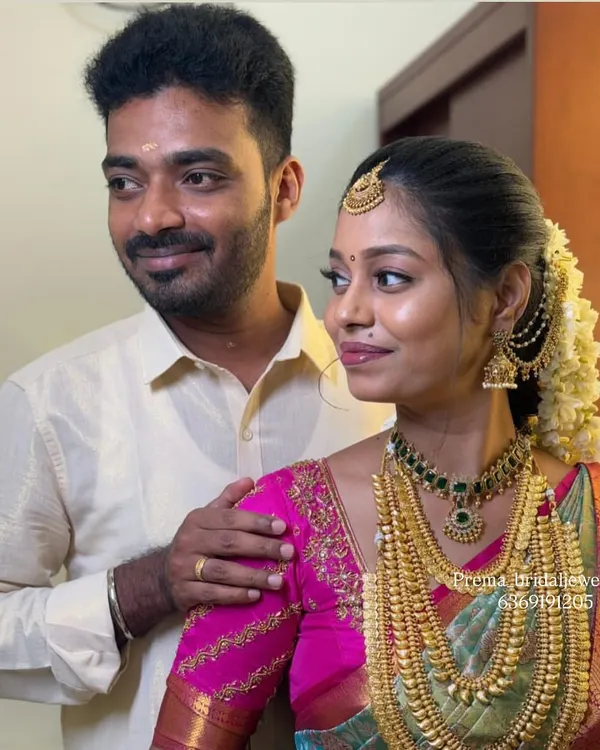 A beautiful moment between the bride and groom. The bride is wearing a stunning layered temple jewellery set that complements her pink and green saree.