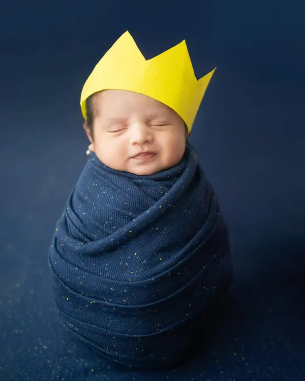 Our little king, wrapped snugly and dreaming big. This simple yet royal setup with a paper crown highlights the precious innocence of a newborn.