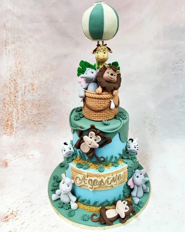 Our Animal Adventure Theme Cake is the epitome of whimsical storytelling. This two-tier masterpiece features a charming hot air balloon carrying a lion, elephant, and giraffe, while monkeys and hippos play below, showcasing our ability to create complex, multi-character scenes with meticulous fondant artistry.