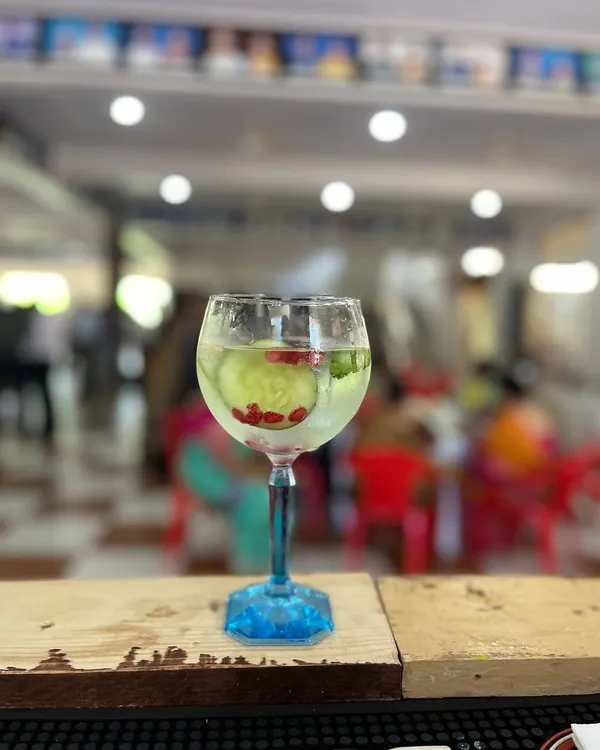 A refreshing Gin and Tonic, perfectly presented in a balloon glass. This classic drink is garnished with a ribbon of cucumber and pomegranate seeds, showing our attention to detail.
