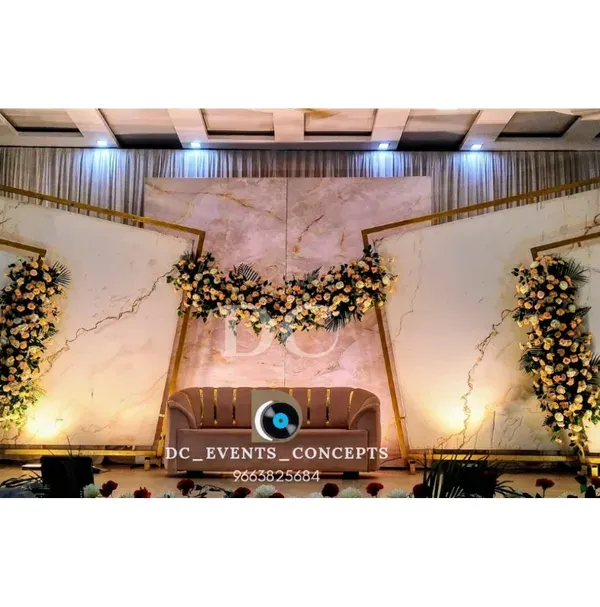 A wide-angle view of a contemporary reception stage featuring a striking white marble-effect backdrop. The geometric gold frames and cascading florals add a touch of modern luxury, perfect for a stylish wedding.